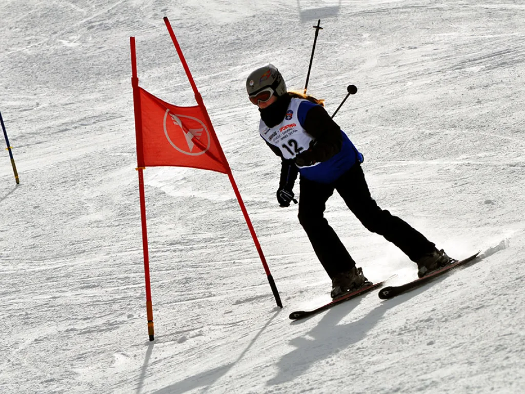 Snowboarderin mit Startnummer 12 fährt am roten Tor vorbei.